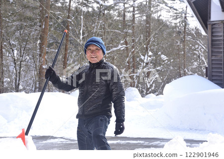 一位微笑的老人使用鏟雪機在雪地裡除雪 122901946