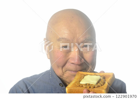 An elderly man eating toasted bread with a smile 122901970