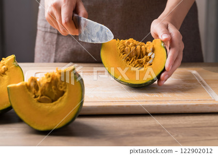 Hand holding kitchen knife and cutting green pumpkin on wooden board, Homemade cooking Hand holding kitchen knife and cutting green pumpkin on wooden board, Homemade cooking 122902012