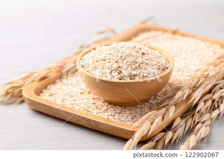 Oat flakes in wooden bowl and plate, Food ingredient in oatmeal, muesli or porridge 122902067