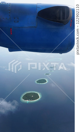Airplane flying over tropical islands in maldives 122902110