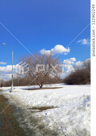 Spring time landscape with melting snow, road, trees and blue sky on sunny March day. Beginning of spring Spring time landscape with melting snow, road, trees and blue sky on sunny March day. Beginning of spring 122902249
