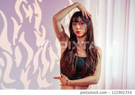 Model poses elegantly in a stylish studio with creative lighting and artistic backdrop 122902358