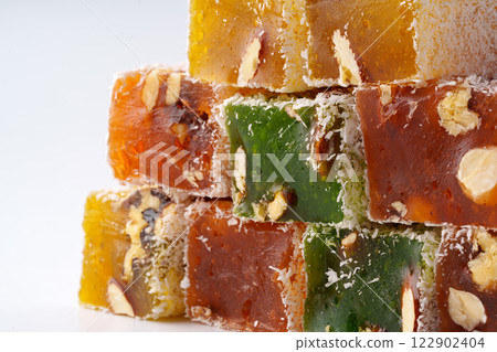 Colorful Turkish delight squares stacked with nuts and coconut flakes on a light background Colorful Turkish delight squares stacked with nuts and coconut flakes on a light background 122902404