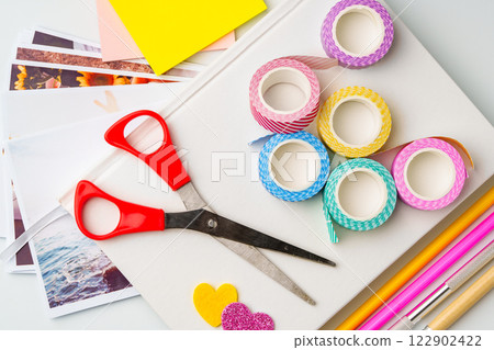 Crafting materials spread on a table for creative projects with scissors, washi tape, and colored paper Crafting materials spread on a table for creative projects with scissors, washi tape, and colored paper 122902422