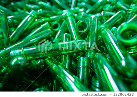 Transparent green plastic tubes piled together in a factory setting during daylight hours 122902428