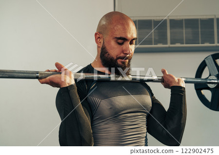 Strong man lifting barbell in a gym during strength training session to build muscle and improve fitness Strong man lifting barbell in a gym during strength training session to build muscle and improve fitness 122902475