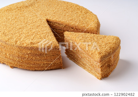 Delicious layered honey cake served on a white plate with a slice cut out for tasting 122902482