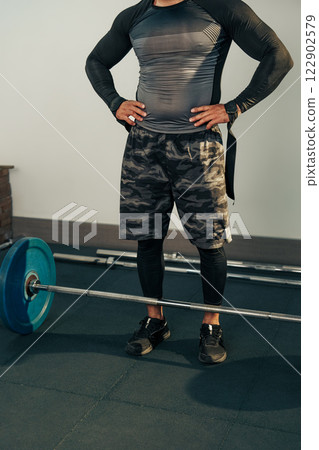 Fitness enthusiast preparing for weightlifting in a gym with a barbell and weights at an indoor training facility 122902579