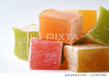 Colorful fruit-flavored jelly cubes attractively arranged on a white surface showcasing their vibrant hues Colorful fruit-flavored jelly cubes attractively arranged on a white surface showcasing their vibrant hues 122902588