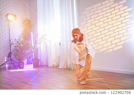 Dancer performing a contemporary routine in a bright studio with creative lighting and serene atmosphere 122902708