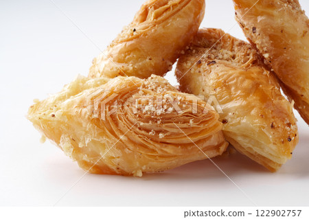 Crispy pastry dessert filled with nuts and syrup showcased on a white background during a culinary presentation 122902757