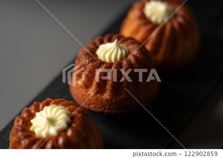 Delicious mini bundt cakes displayed on a dark platter with creamy frosting on top 122902859