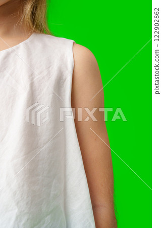 A child stands in front of a bright green background close up 122902862