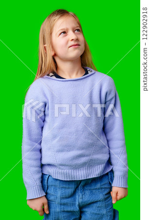 A young child in a light purple sweater gazes against a green background while deep in thought A young child in a light purple sweater gazes against a green background while deep in thought 122902918