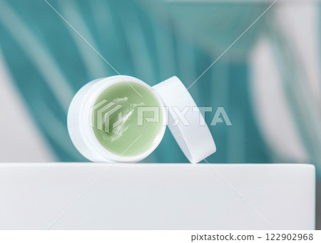 Opened white blank lip balm jar on wash basin in green tropical bathroom close up, cosmetic mockup 122902968