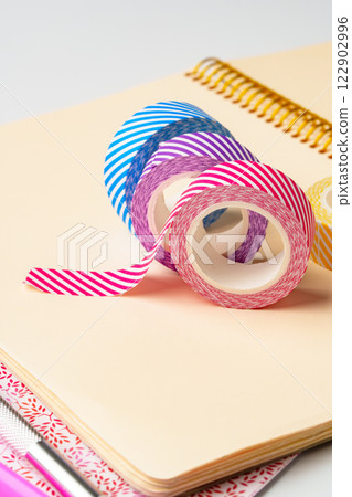 Colorful washi tape rolls arranged on a notepad with a spiral binding for crafting and decoration purposes 122902996