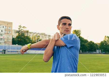 Young athlete stretches before training on a grassy field in the late afternoon sun Young athlete stretches before training on a grassy field in the late afternoon sun 122903051