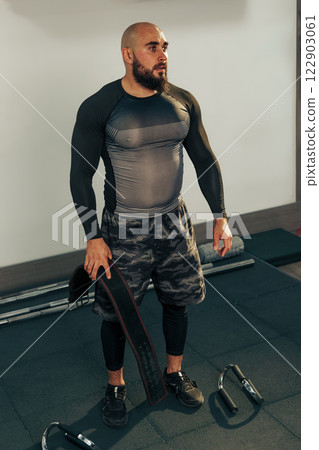 Strong man engages in workout at gym focusing on strength training and fitness routine Strong man engages in workout at gym focusing on strength training and fitness routine 122903061