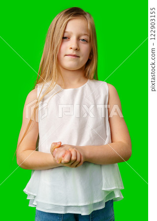 Young girl standing confidently against a bright green background 122903155