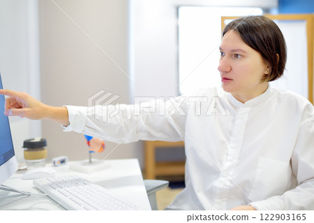 A cardiologist during appointment of patient. Doctor shows EKG on the screen of computer and explains about deviations of heart work. Cardiology consultation and treatment 122903165