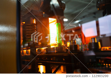 Manufacturing process showcasing a glowing green object in a modern industrial facility 122903200