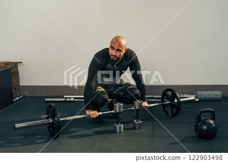 Fitness enthusiast engaged in strength training with weights in a gym setting during the evening 122903498