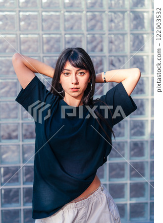 Confident young woman posing with her hair pulled back in a minimalistic studio setting during daylight hours Confident young woman posing with her hair pulled back in a minimalistic studio setting during daylight hours 122903532