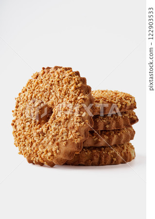 Delicious round cookies coated in crushed nuts stacked artistically on a neutral background for a mouthwatering display Delicious round cookies coated in crushed nuts stacked artistically on a neutral background for a mouthwatering display 122903533