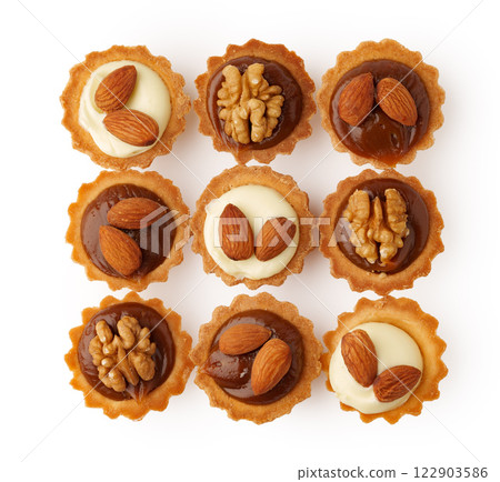 Assorted mini pastries topped with nuts arranged in a neat grid on a white background 122903586