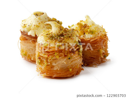 Delicious stacked pastry with cream and nut topping served on a white background for an enticing dessert experience Delicious stacked pastry with cream and nut topping served on a white background for an enticing dessert experience 122903703