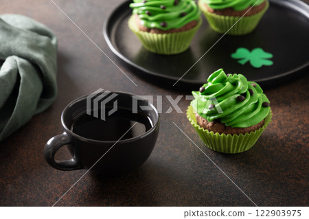 St. Patrick's Day coffee and homemade cupcakes with green whipped cream and chocolate sprinkles on brown background. Close up. St. Patrick's Day coffee and homemade cupcakes with green whipped cream and chocolate sprinkles on brown background. Close up. 122903975