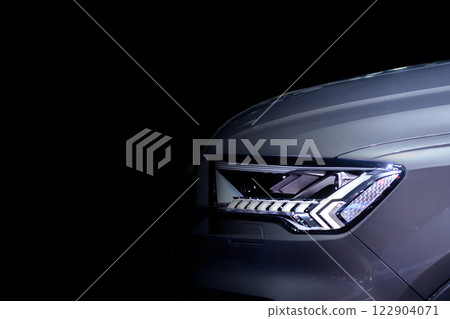 Close-up front headlight with LED xenon light of grey modern EV Car on black colour background and copy space 122904071
