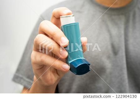 Asthma and chronic obstructive pulmonary disease COPD, Asian young man using metered dose inhaler MDI. 122904130