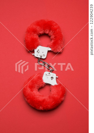 Red sexy fluffy handcuffs on a red 122904239