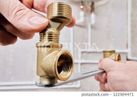 Brass elbow fitting with an internal threaded connection is being installed along with an eccentric reducer, ensuring proper alignment in plumbing system. 122904471