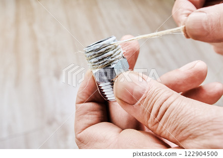 Hex nipple adapter is being wrapped with plumbing hemp and sealing paste, ensuring threaded pipe fitting is properly sealed before installation Hex nipple adapter is being wrapped with plumbing hemp and sealing paste, ensuring threaded pipe fitting is properly sealed before installation 122904500