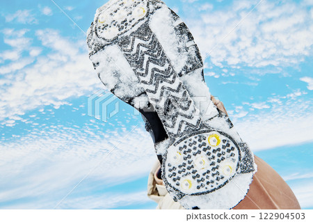 Traction cleats on a snow covered boot, low perspective, sky background. 122904503
