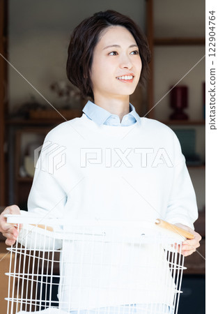 Woman holding a laundry basket and looking out the window Woman holding a laundry basket and looking out the window 122904764