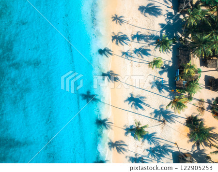 Aerial view of sandy beach, shadows of palms, blue sea at sunset Aerial view of sandy beach, shadows of palms, blue sea at sunset 122905253
