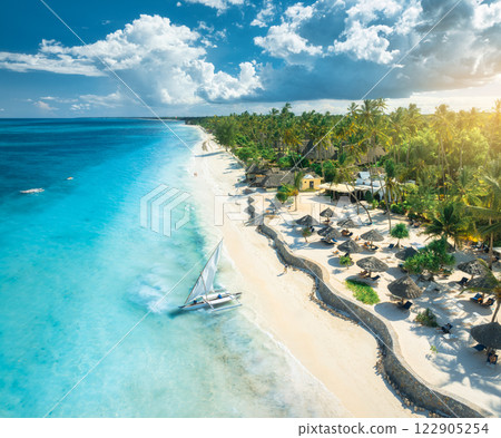 Aerial view of the sailboat on blue sea, empty white sandy beach Aerial view of the sailboat on blue sea, empty white sandy beach 122905254