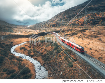 Aerial view of red train, river, mountains, orange hills in fall Aerial view of red train, river, mountains, orange hills in fall 122905274
