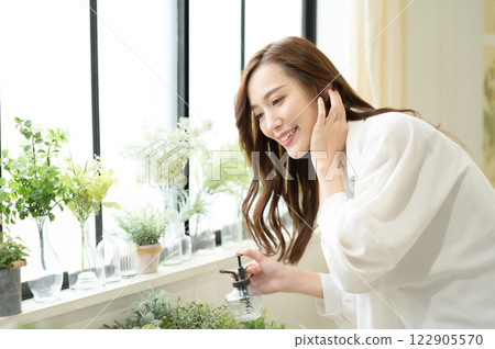 A woman spraying mist on a houseplant 122905570