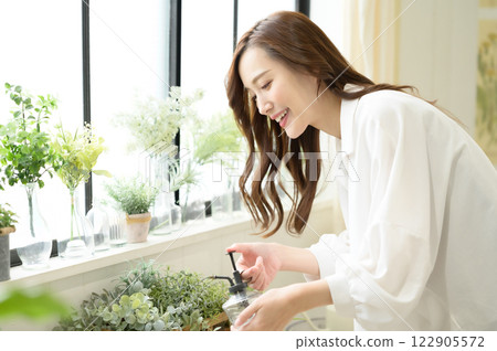 A woman spraying mist on a houseplant A woman spraying mist on a houseplant 122905572