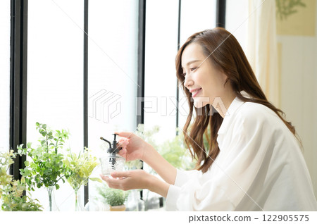 一名婦女正在為室內植物噴灑噴霧 一名婦女正在為室內植物噴灑噴霧 122905575