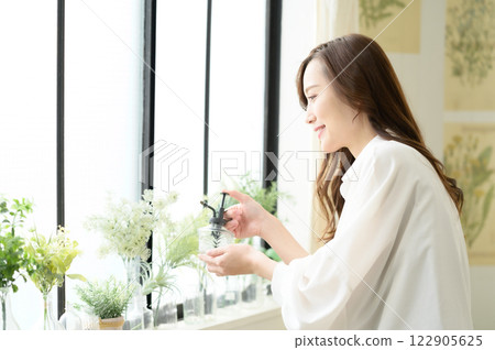 A woman spraying mist on a houseplant 122905625