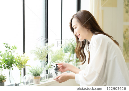 A woman spraying mist on a houseplant 122905626