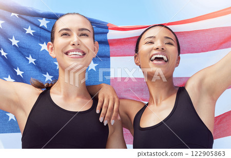 USA flag, sports winner and women winning race at sport stadium, happy with teamwork in marathon and smile for success at running competition. Athlete runner team in celebration and support at event 122905863