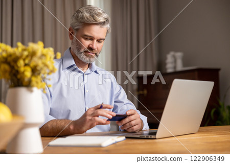 Mature caucasian man working at the laptop and looking confident Mature caucasian man working at the laptop and looking confident 122906349