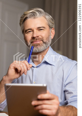 Waist up of a mid aged bearded man with a notebook and a pen in hand 122906391